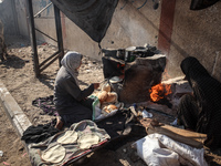 A Palestinian woman bakes bread at a makeshift camp for the internally displaced in Deir al-Balah in the central Gaza Strip on October 18, 2...