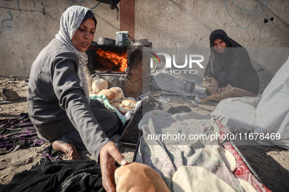 A Palestinian woman bakes bread at a makeshift camp for the internally displaced in Deir al-Balah in the central Gaza Strip on October 18, 2...