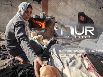 A Palestinian woman bakes bread at a makeshift camp for the internally displaced in Deir al-Balah in the central Gaza Strip on October 18, 2...