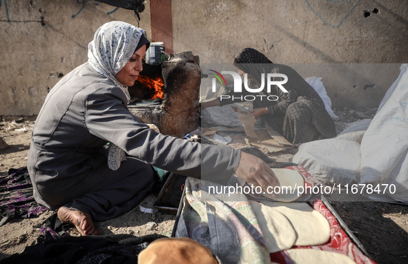 A Palestinian woman bakes bread at a makeshift camp for the internally displaced in Deir al-Balah in the central Gaza Strip on October 18, 2...