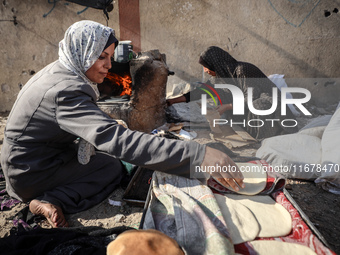 A Palestinian woman bakes bread at a makeshift camp for the internally displaced in Deir al-Balah in the central Gaza Strip on October 18, 2...