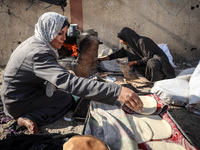 A Palestinian woman bakes bread at a makeshift camp for the internally displaced in Deir al-Balah in the central Gaza Strip on October 18, 2...