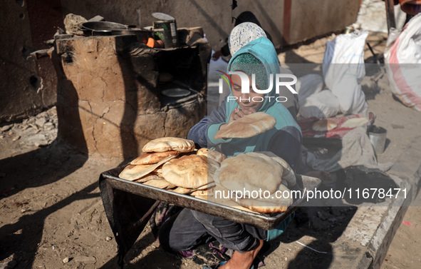 A Palestinian girl carries freshly baked loaves of bread at a makeshift camp for the internally displaced in Deir al-Balah, Gaza Strip, on O...