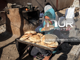 A Palestinian girl carries freshly baked loaves of bread at a makeshift camp for the internally displaced in Deir al-Balah, Gaza Strip, on O...