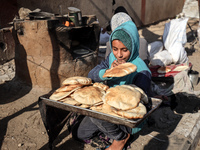 A Palestinian girl carries freshly baked loaves of bread at a makeshift camp for the internally displaced in Deir al-Balah, Gaza Strip, on O...