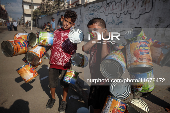 Displaced Palestinian children carry empty cans to sell in the market in Deir al-Balah, Gaza Strip, on October 18, 2024, amid the ongoing wa...