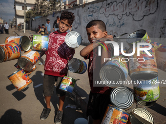 Displaced Palestinian children carry empty cans to sell in the market in Deir al-Balah, Gaza Strip, on October 18, 2024, amid the ongoing wa...