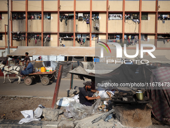 A Palestinian man bakes bread at a makeshift camp for the internally displaced in Deir al-Balah in the central Gaza Strip on October 18, 202...