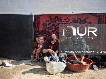 Palestinian women wash their clothes at a makeshift camp for the internally displaced in Deir al-Balah, Gaza Strip, on October 18, 2024, ami...