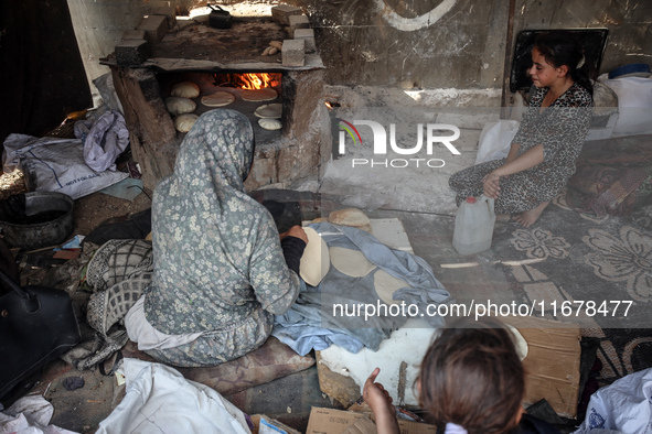 A Palestinian woman bakes bread at a makeshift camp for the internally displaced in Deir al-Balah in the central Gaza Strip on October 18, 2...