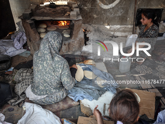 A Palestinian woman bakes bread at a makeshift camp for the internally displaced in Deir al-Balah in the central Gaza Strip on October 18, 2...