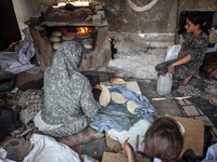 A Palestinian woman bakes bread at a makeshift camp for the internally displaced in Deir al-Balah in the central Gaza Strip on October 18, 2...