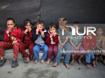 Displaced Palestinian children sit in front of a tent at a makeshift camp for the internally displaced in Deir al-Balah in the central Gaza...