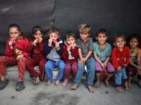 Displaced Palestinian children sit in front of a tent at a makeshift camp for the internally displaced in Deir al-Balah in the central Gaza...