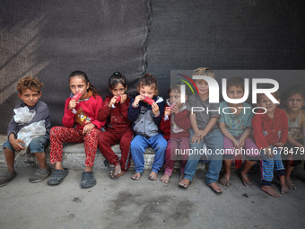 Displaced Palestinian children sit in front of a tent at a makeshift camp for the internally displaced in Deir al-Balah in the central Gaza...