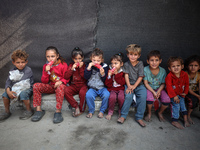 Displaced Palestinian children sit in front of a tent at a makeshift camp for the internally displaced in Deir al-Balah in the central Gaza...