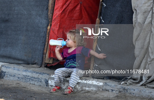 A displaced Palestinian child sits in front of a tent in a temporary camp for internally displaced persons in Deir al-Balah, central Gaza St...