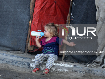 A displaced Palestinian child sits in front of a tent in a temporary camp for internally displaced persons in Deir al-Balah, central Gaza St...