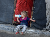 A displaced Palestinian child sits in front of a tent in a temporary camp for internally displaced persons in Deir al-Balah, central Gaza St...