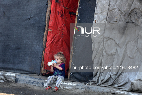 A displaced Palestinian child sits in front of a tent in a temporary camp for internally displaced persons in Deir al-Balah, central Gaza St...