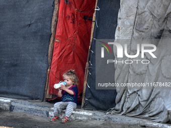 A displaced Palestinian child sits in front of a tent in a temporary camp for internally displaced persons in Deir al-Balah, central Gaza St...