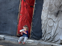 A displaced Palestinian child sits in front of a tent in a temporary camp for internally displaced persons in Deir al-Balah, central Gaza St...