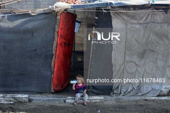 A displaced Palestinian child sits in front of a tent in a temporary camp for internally displaced persons in Deir al-Balah, central Gaza St...