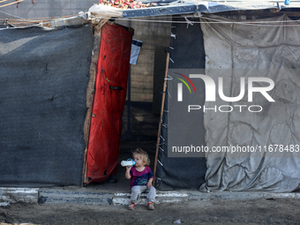 A displaced Palestinian child sits in front of a tent in a temporary camp for internally displaced persons in Deir al-Balah, central Gaza St...