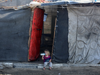 A displaced Palestinian child sits in front of a tent in a temporary camp for internally displaced persons in Deir al-Balah, central Gaza St...