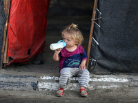 A displaced Palestinian child sits in front of a tent in a temporary camp for internally displaced persons in Deir al-Balah, central Gaza St...