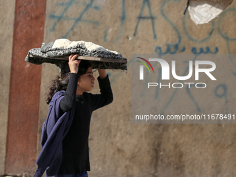 A Palestinian girl carries freshly baked loaves of bread back to her family at a makeshift camp for the internally displaced in Deir al-Bala...