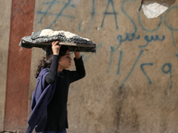 A Palestinian girl carries freshly baked loaves of bread back to her family at a makeshift camp for the internally displaced in Deir al-Bala...