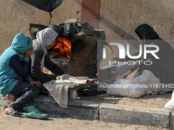 A Palestinian woman bakes bread at a makeshift camp for the internally displaced in Deir al-Balah in the central Gaza Strip on October 18, 2...