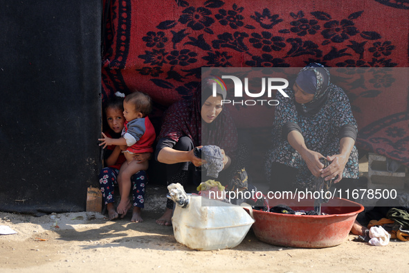 Palestinian women wash their clothes at a makeshift camp for the internally displaced in Deir al-Balah, Gaza Strip, on October 18, 2024, ami...