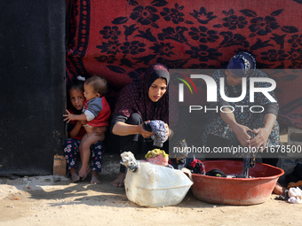 Palestinian women wash their clothes at a makeshift camp for the internally displaced in Deir al-Balah, Gaza Strip, on October 18, 2024, ami...