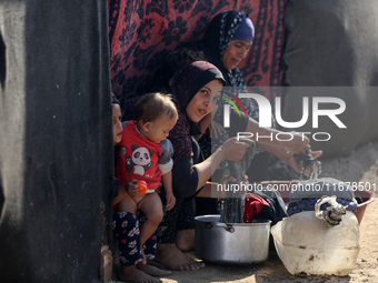 Palestinian women wash their clothes at a makeshift camp for the internally displaced in Deir al-Balah, Gaza Strip, on October 18, 2024, ami...