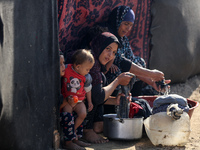 Palestinian women wash their clothes at a makeshift camp for the internally displaced in Deir al-Balah, Gaza Strip, on October 18, 2024, ami...