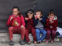 Displaced Palestinian children sit in front of a tent at a makeshift camp for the internally displaced in Deir al-Balah in the central Gaza...