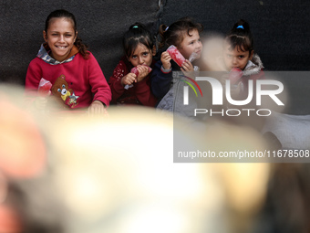 Displaced Palestinian children sit in front of a tent at a makeshift camp for the internally displaced in Deir al-Balah in the central Gaza...