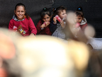 Displaced Palestinian children sit in front of a tent at a makeshift camp for the internally displaced in Deir al-Balah in the central Gaza...