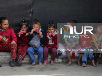 Displaced Palestinian children sit in front of a tent at a makeshift camp for the internally displaced in Deir al-Balah in the central Gaza...