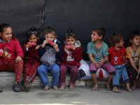 Displaced Palestinian children sit in front of a tent at a makeshift camp for the internally displaced in Deir al-Balah in the central Gaza...