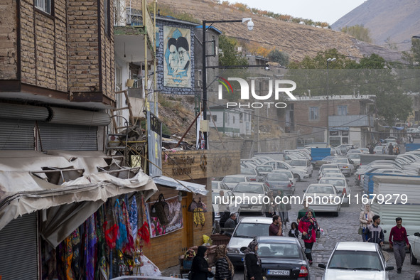 Iranian people walk under portraits of Iran's Supreme Leader, Ayatollah Ali Khamenei, and late leader, Ayatollah Ruhollah Khomeini, while vi...