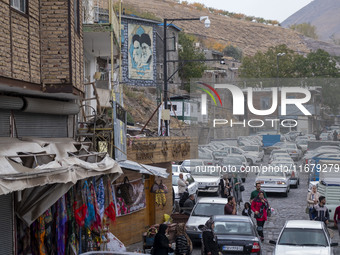 Iranian people walk under portraits of Iran's Supreme Leader, Ayatollah Ali Khamenei, and late leader, Ayatollah Ruhollah Khomeini, while vi...