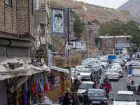 Iranian people walk under portraits of Iran's Supreme Leader, Ayatollah Ali Khamenei, and late leader, Ayatollah Ruhollah Khomeini, while vi...