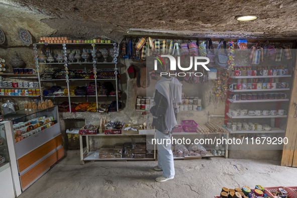 A young Iranian woman looks at goods while shopping during her visit to the Kandovan cliff village in Kandovan, Iran, on October 18, 2024. K...