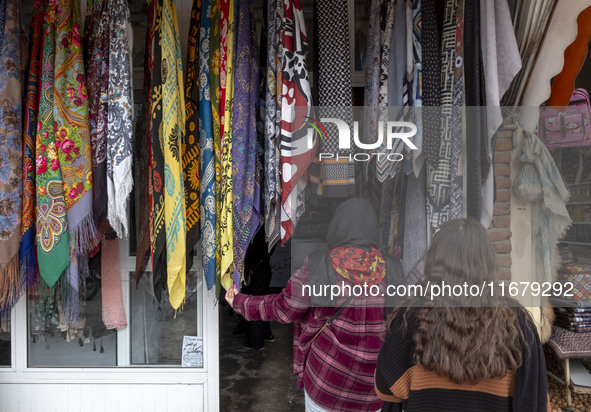 A young Iranian woman looks at scarves hanging outside a handicraft shop in Kandovan cliff village, located 650 km (400 miles) northwest of...