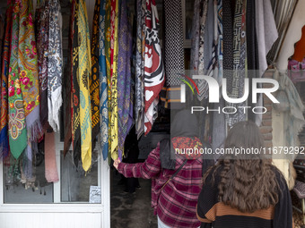 A young Iranian woman looks at scarves hanging outside a handicraft shop in Kandovan cliff village, located 650 km (400 miles) northwest of...