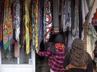 A young Iranian woman looks at scarves hanging outside a handicraft shop in Kandovan cliff village, located 650 km (400 miles) northwest of...