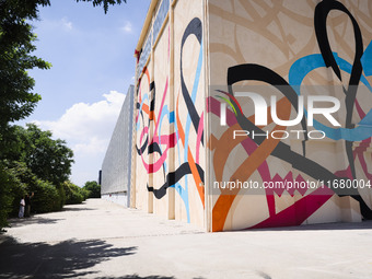 A moment of the press presentation of the mural Waves Only Exist Because the Wind Blows by eL Seed on the exterior walls of Pirelli HangarBi...